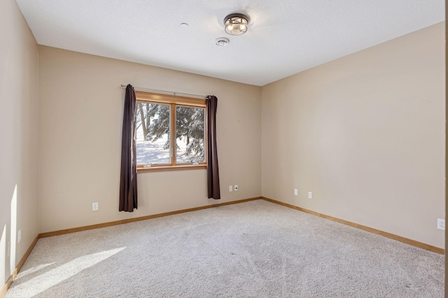 carpeted empty room featuring baseboards