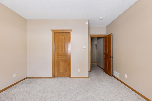 spare room with light colored carpet, visible vents, and baseboards