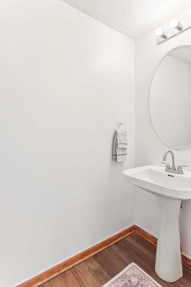 bathroom with a sink, a textured ceiling, baseboards, and wood finished floors