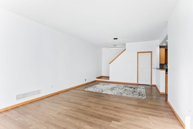 unfurnished room with light wood finished floors, visible vents, and baseboards