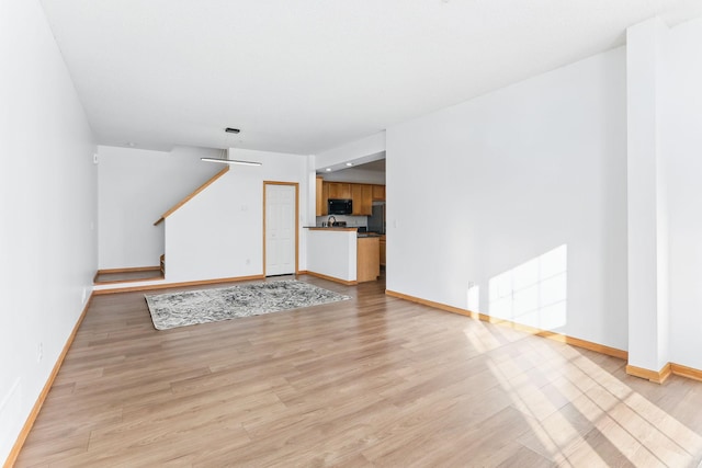 unfurnished living room with light wood-style floors and baseboards