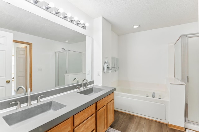 bathroom with a textured ceiling, wood finished floors, a sink, and a bath