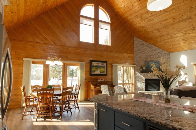 kitchen featuring high vaulted ceiling, freestanding refrigerator, wood walls, healthy amount of natural light, and open floor plan