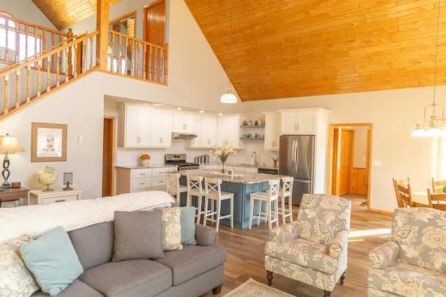 living area featuring wood ceiling, high vaulted ceiling, stairway, light wood-type flooring, and a chandelier