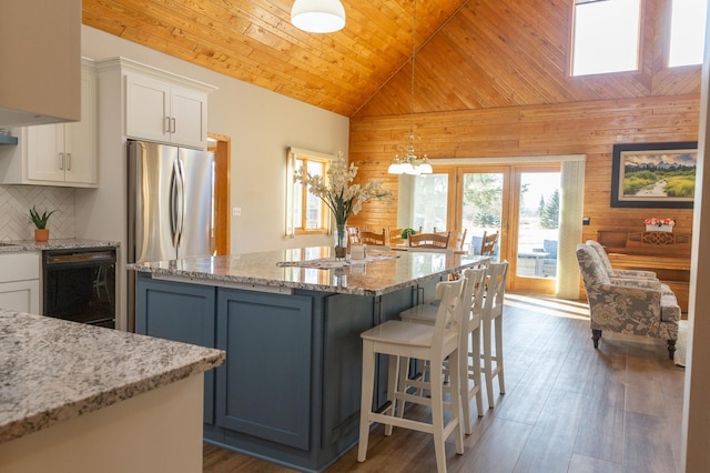 kitchen with wooden walls, a kitchen bar, wood ceiling, a center island, and white cabinets