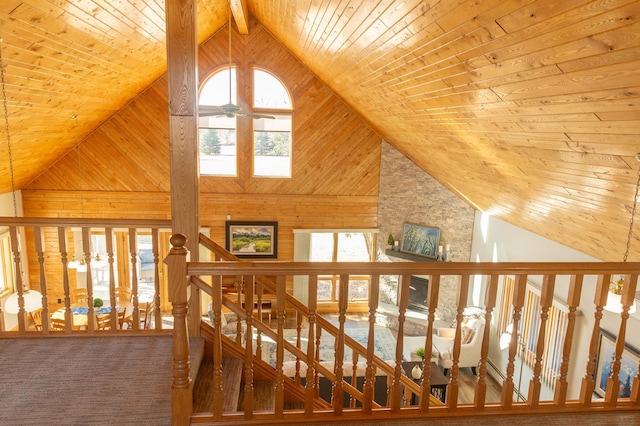 hall featuring wooden ceiling, wooden walls, an upstairs landing, and high vaulted ceiling