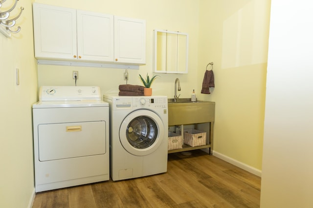 laundry room with washing machine and clothes dryer, cabinet space, wood finished floors, and baseboards