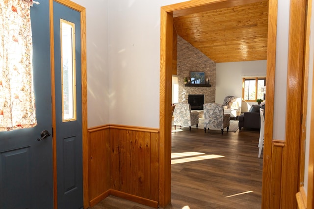 entryway with vaulted ceiling, wood ceiling, a wainscoted wall, a fireplace, and wood finished floors
