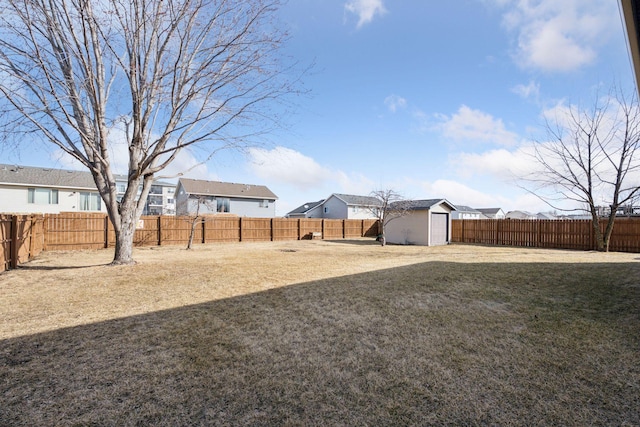 view of yard featuring a fenced backyard, a residential view, a storage shed, and an outdoor structure