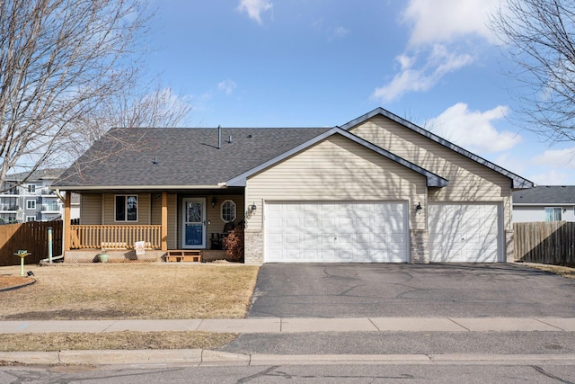 ranch-style home featuring a porch, fence, a garage, and aphalt driveway