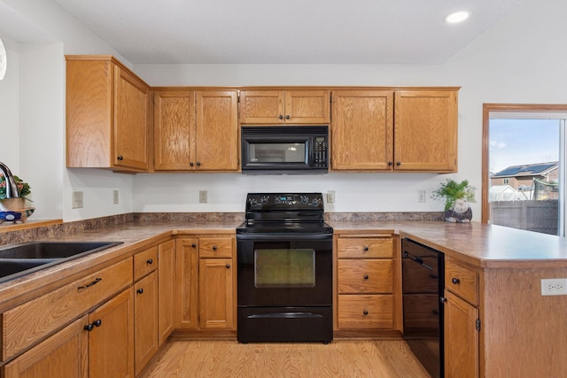 kitchen with black appliances, beverage cooler, a sink, light wood-style floors, and a peninsula