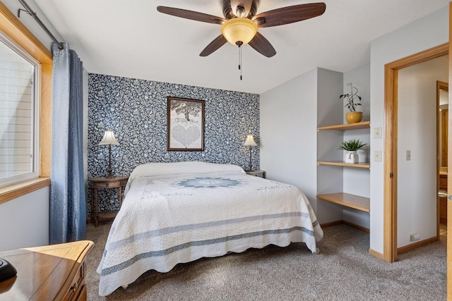 carpeted bedroom with wallpapered walls, a ceiling fan, baseboards, and an accent wall