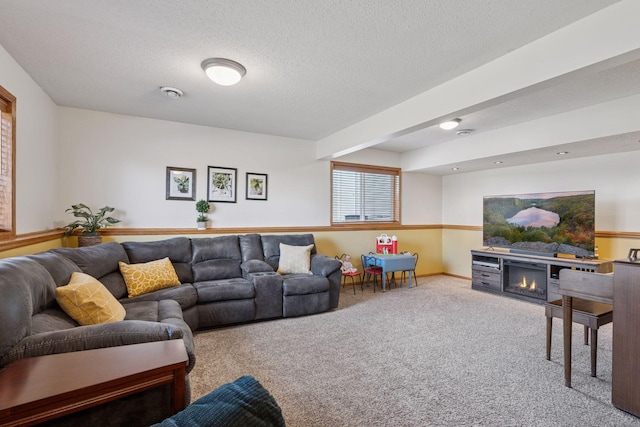 carpeted living area featuring a lit fireplace and a textured ceiling