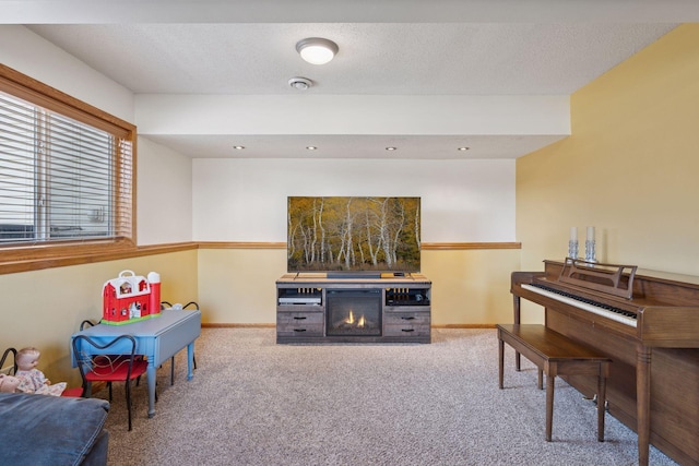 interior space featuring carpet flooring, baseboards, a lit fireplace, and a textured ceiling