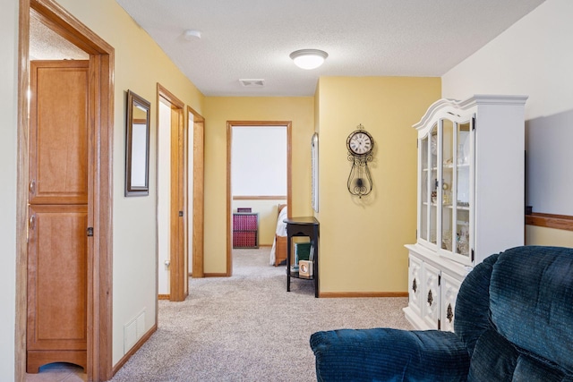 sitting room with carpet flooring, baseboards, visible vents, and a textured ceiling