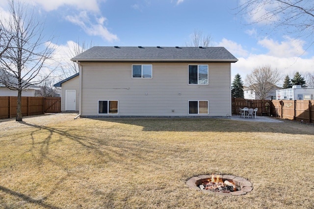 back of house featuring a patio, an outdoor fire pit, a yard, a fenced backyard, and a shingled roof