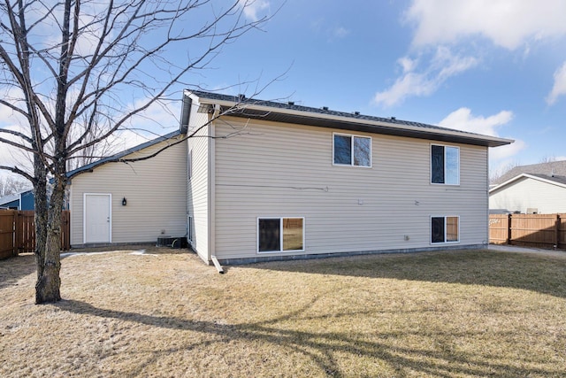 rear view of house featuring a lawn and a fenced backyard