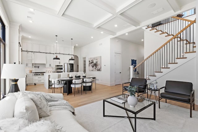 living area featuring stairs, light wood-type flooring, beam ceiling, and recessed lighting