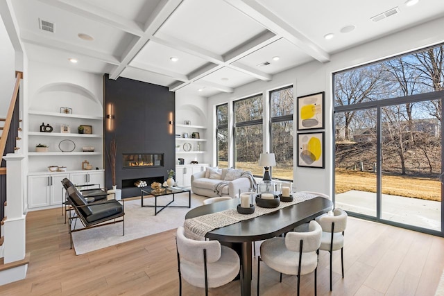 dining space featuring a large fireplace, coffered ceiling, beamed ceiling, and light wood finished floors