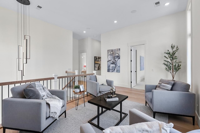 living area featuring visible vents, baseboards, light wood-style flooring, and recessed lighting