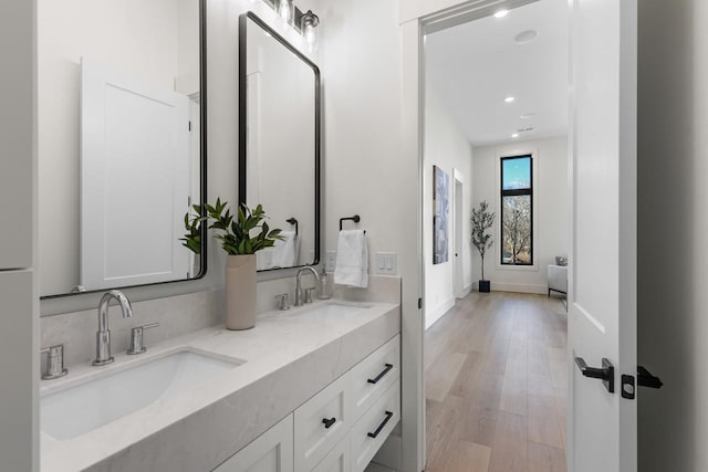 full bathroom featuring double vanity, a sink, baseboards, and wood finished floors