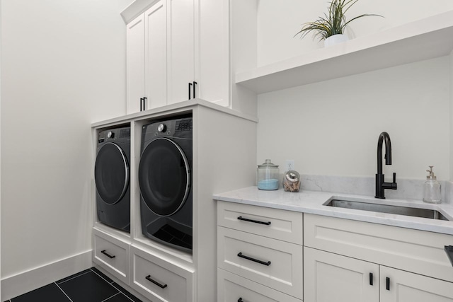 laundry room with cabinet space, baseboards, tile patterned flooring, washer and dryer, and a sink