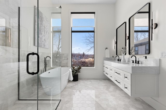 full bath with double vanity, a freestanding tub, plenty of natural light, and a sink