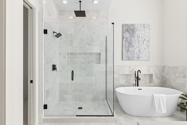 full bath with tile walls, a freestanding bath, and a shower stall