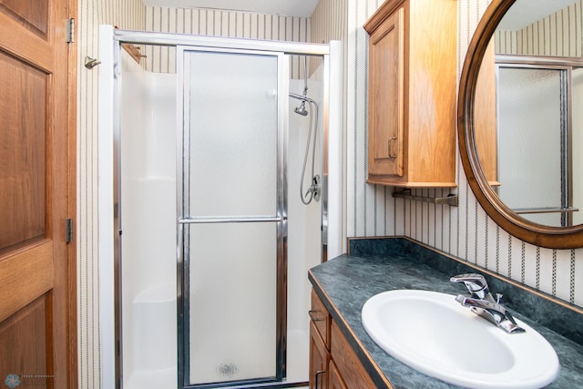 bathroom with a shower stall, wallpapered walls, and vanity