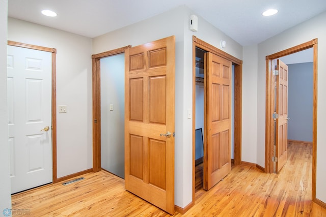 corridor with light wood-type flooring, visible vents, baseboards, and recessed lighting