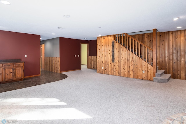 unfurnished living room with carpet, stairway, wood walls, a wainscoted wall, and recessed lighting