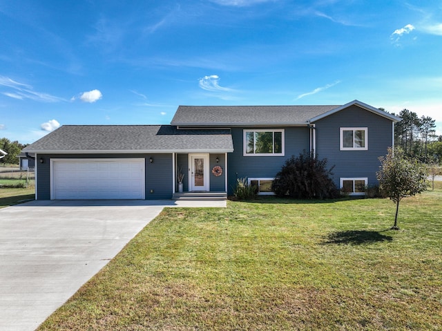 split level home with a garage, driveway, a front lawn, and roof with shingles