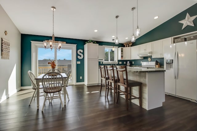 kitchen featuring a breakfast bar area, under cabinet range hood, white appliances, white cabinetry, and dark wood finished floors