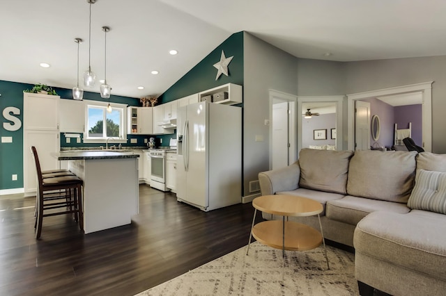 kitchen featuring under cabinet range hood, white appliances, a sink, white cabinetry, and open floor plan