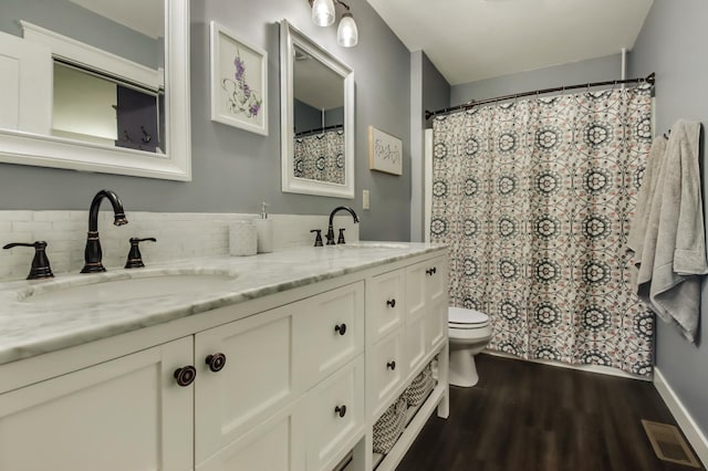 bathroom featuring toilet, visible vents, a sink, and wood finished floors