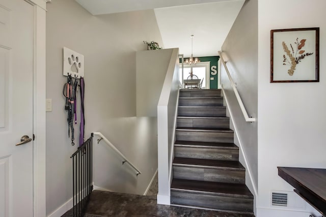 stairs featuring a chandelier, visible vents, and baseboards