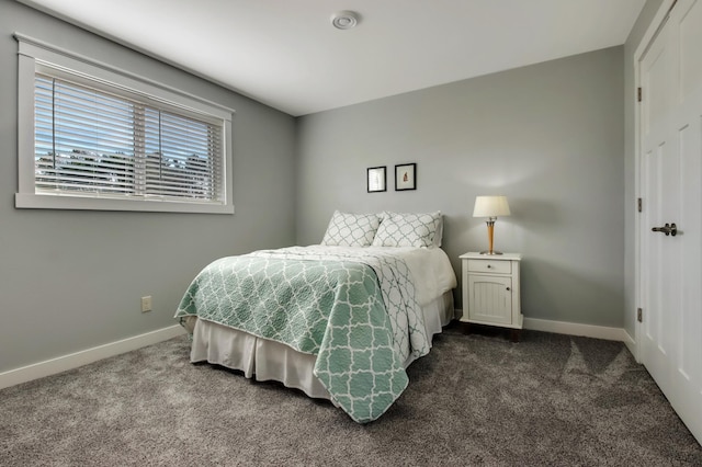 bedroom featuring dark colored carpet and baseboards