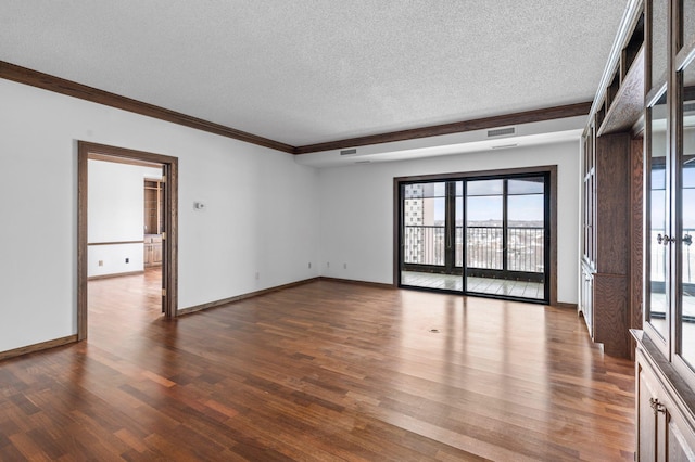 spare room with wood finished floors, baseboards, visible vents, ornamental molding, and a textured ceiling