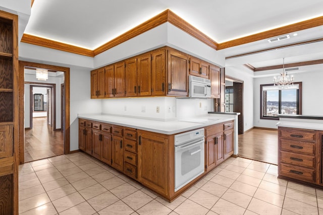 kitchen with white appliances, light tile patterned floors, visible vents, ornamental molding, and a notable chandelier