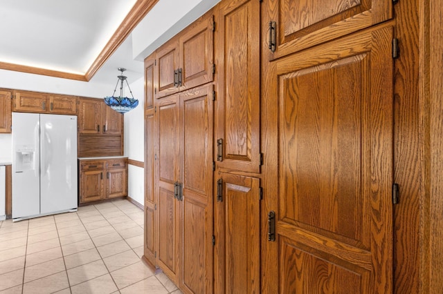 kitchen featuring brown cabinets, white fridge with ice dispenser, light tile patterned flooring, and crown molding