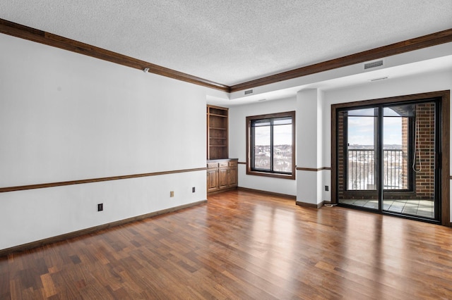 unfurnished room with visible vents, a textured ceiling, baseboards, and wood finished floors