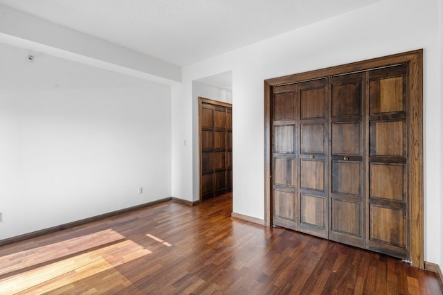 unfurnished bedroom featuring dark wood-type flooring and baseboards