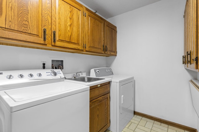 laundry room with washing machine and clothes dryer, baseboards, light floors, cabinet space, and a sink