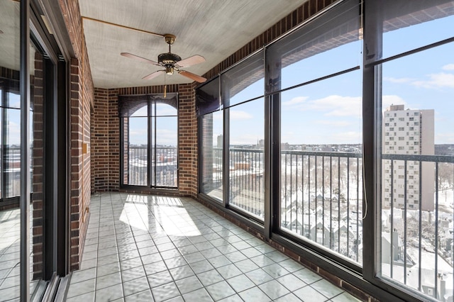 unfurnished sunroom featuring plenty of natural light, a view of city, and a ceiling fan