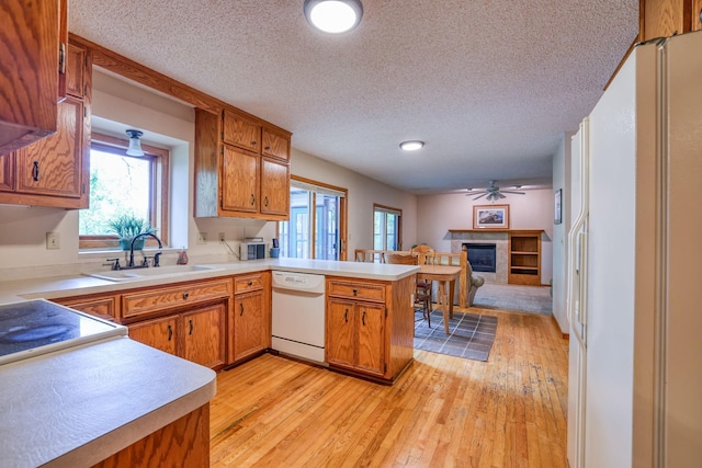 kitchen with white appliances, light countertops, a sink, and a peninsula