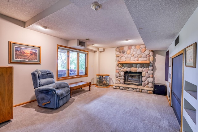 sitting room with visible vents, carpet flooring, a stone fireplace, a textured ceiling, and baseboards