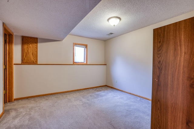 carpeted spare room with visible vents, a textured ceiling, and baseboards