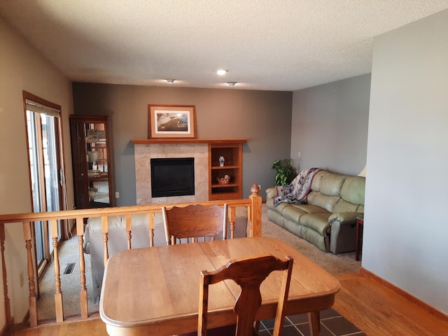 living room with baseboards, visible vents, wood finished floors, a textured ceiling, and a fireplace