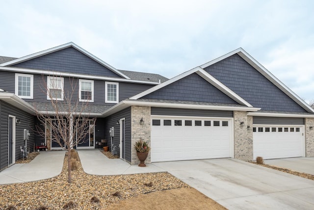 view of front of house featuring brick siding, a garage, driveway, and roof with shingles