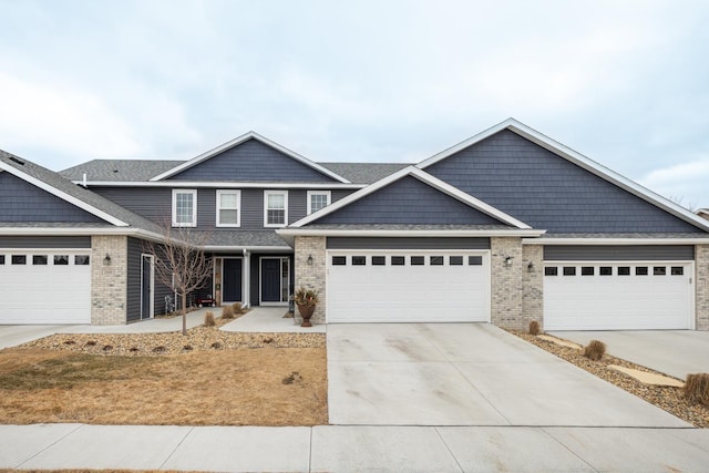 view of front of property featuring brick siding, driveway, an attached garage, and a shingled roof